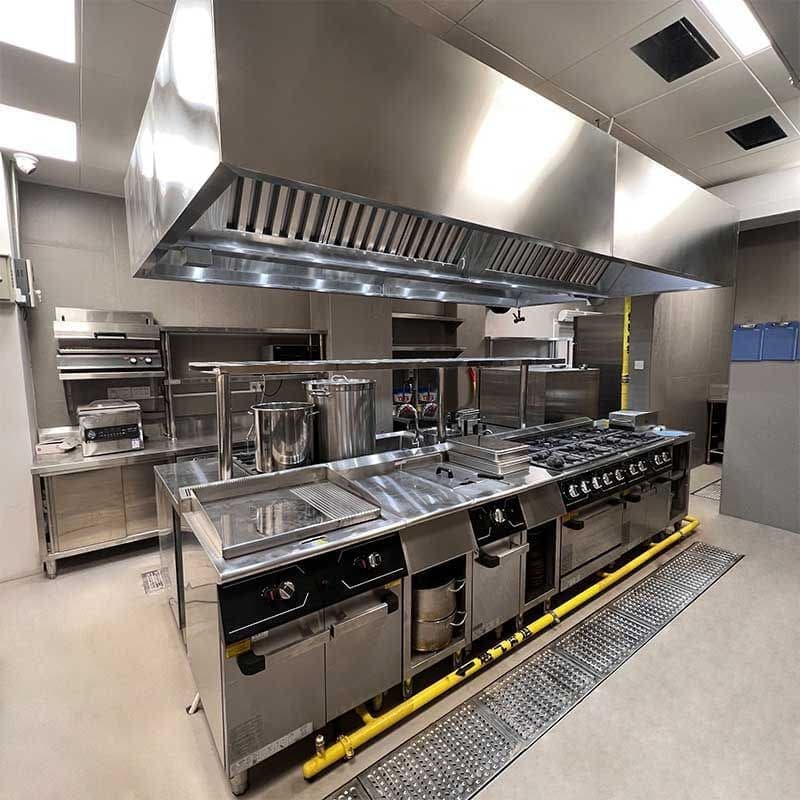 Installed commercial kitchen line with exhaust hood and gas range
